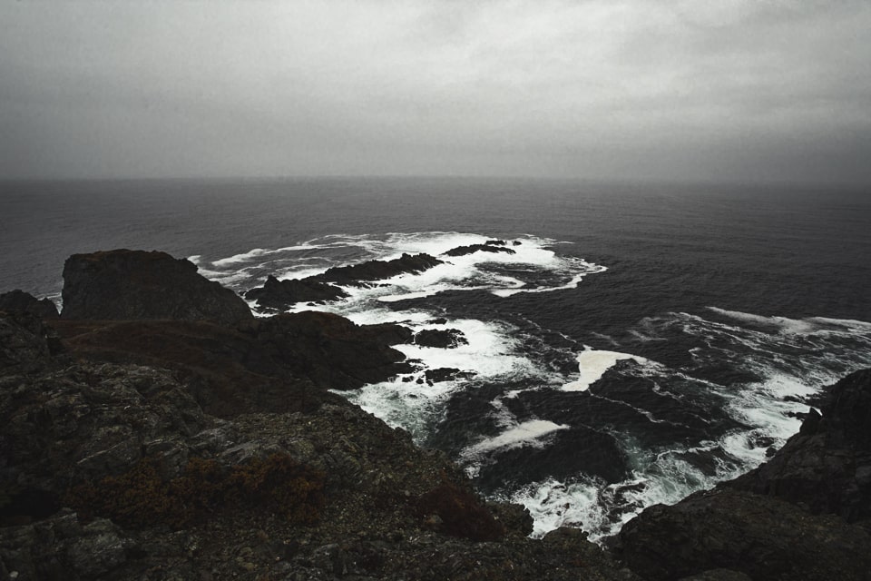 A game of light and shadow, of bright seafoam and dark rocks
